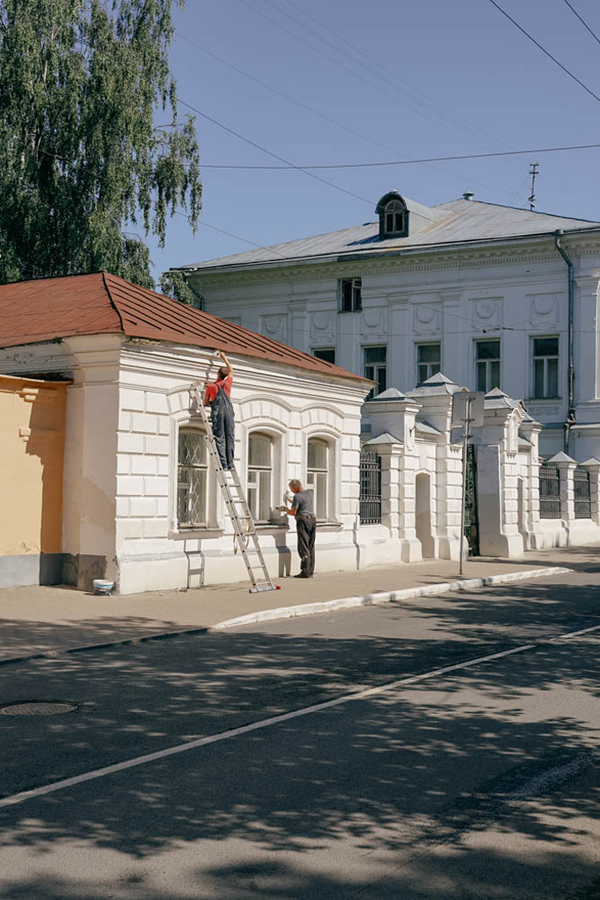 Рабочие красят старинное здание на улоице в Костроме